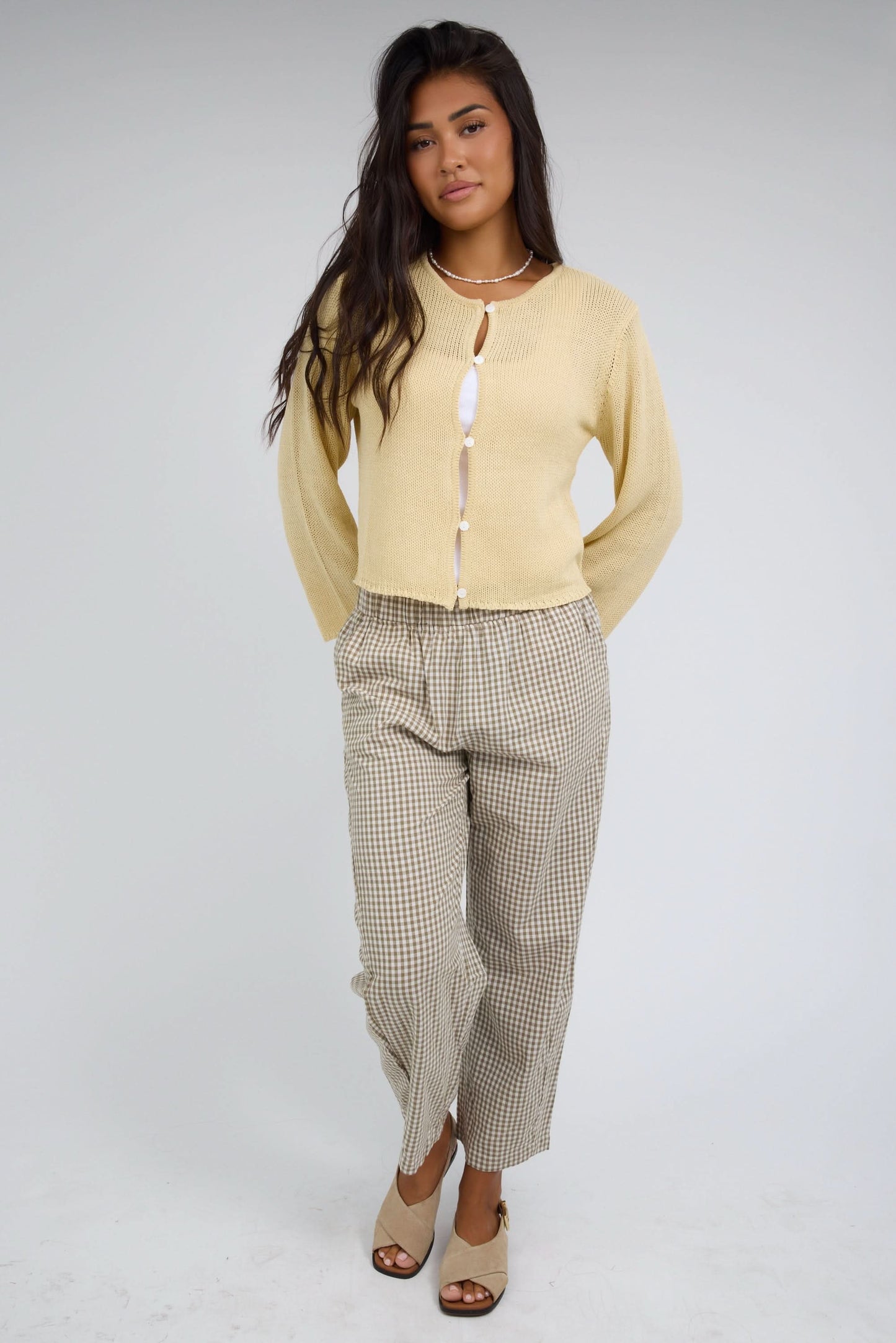 Young woman wearing a yellow loosely knit button down cardigan with long sleeves.