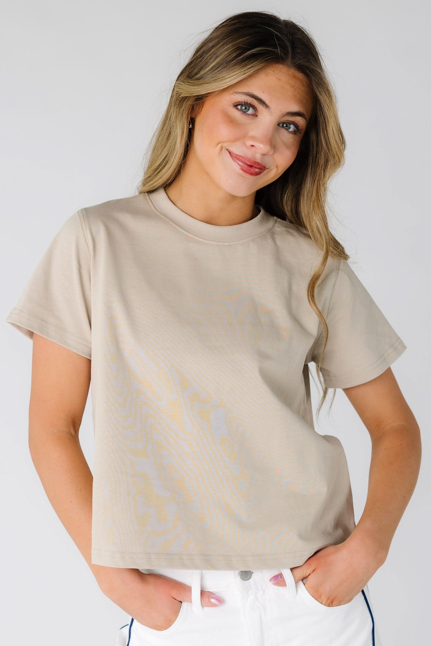 Young woman wearing a modest tan tee with short sleeves and a crew neckline.