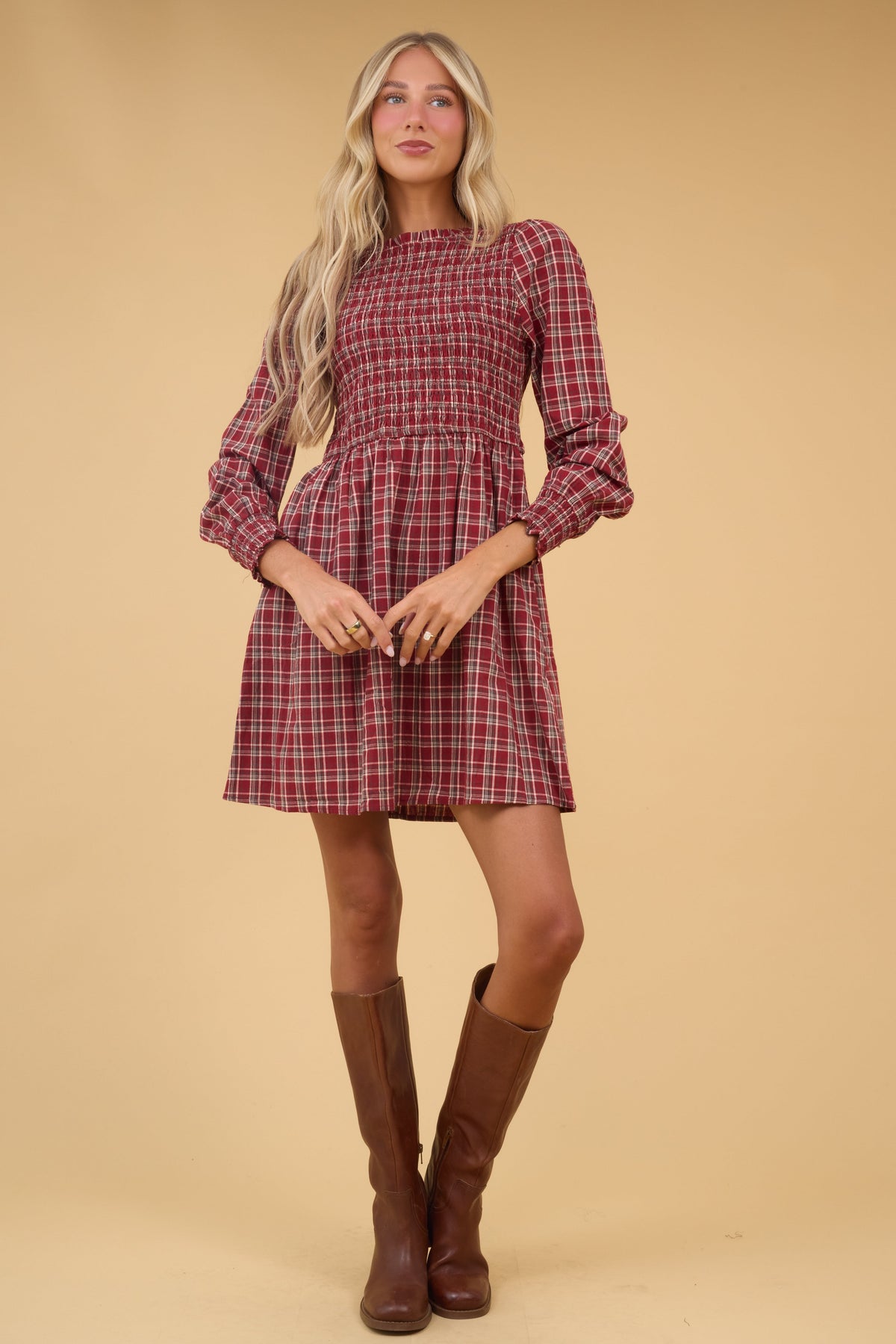 Woman wearing  red plaid dress with long sleeves, smocked bodice and full skirt.