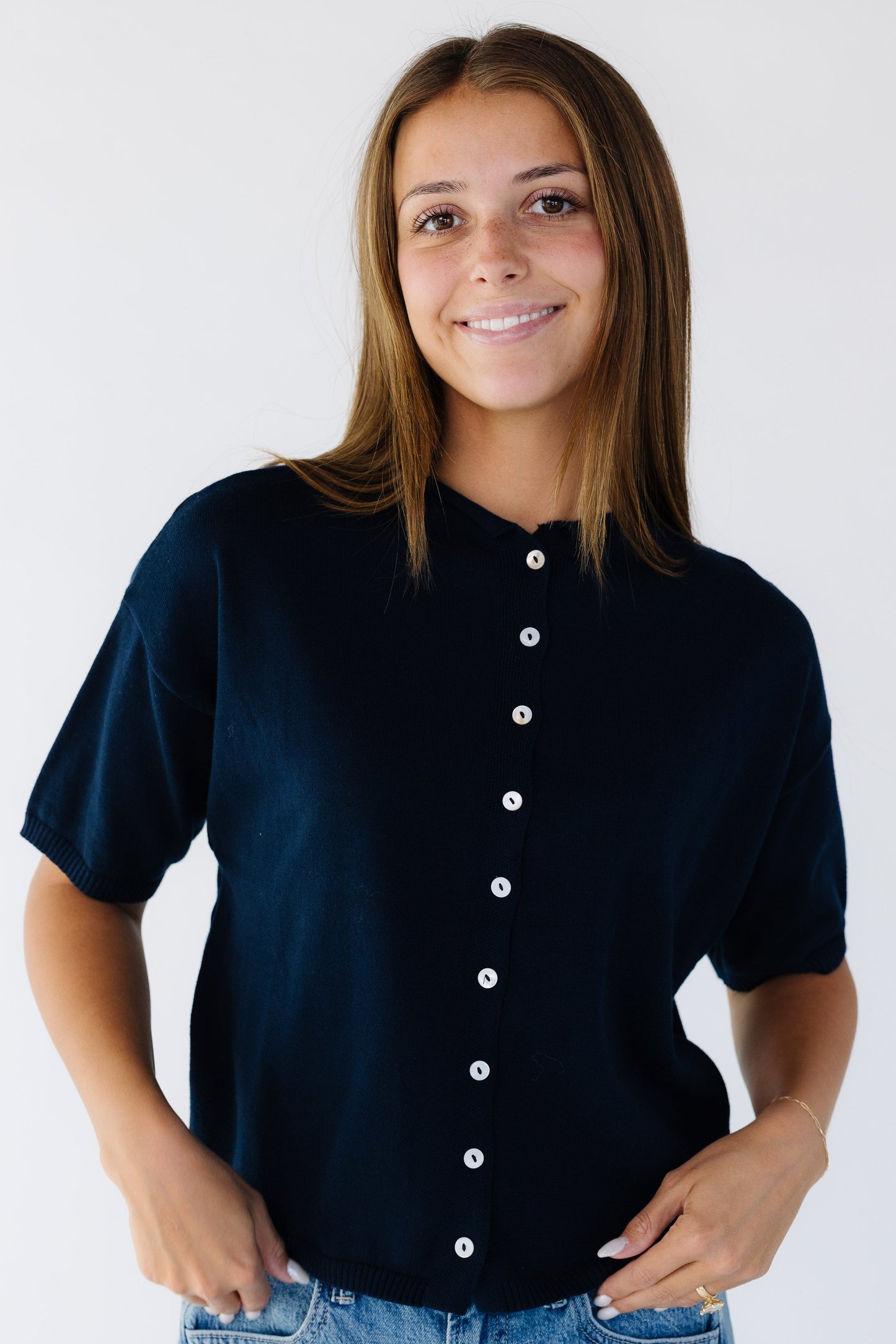 Woman wearing a modest dark navy button down cardigan with short sleeves and a round rolled neckline.