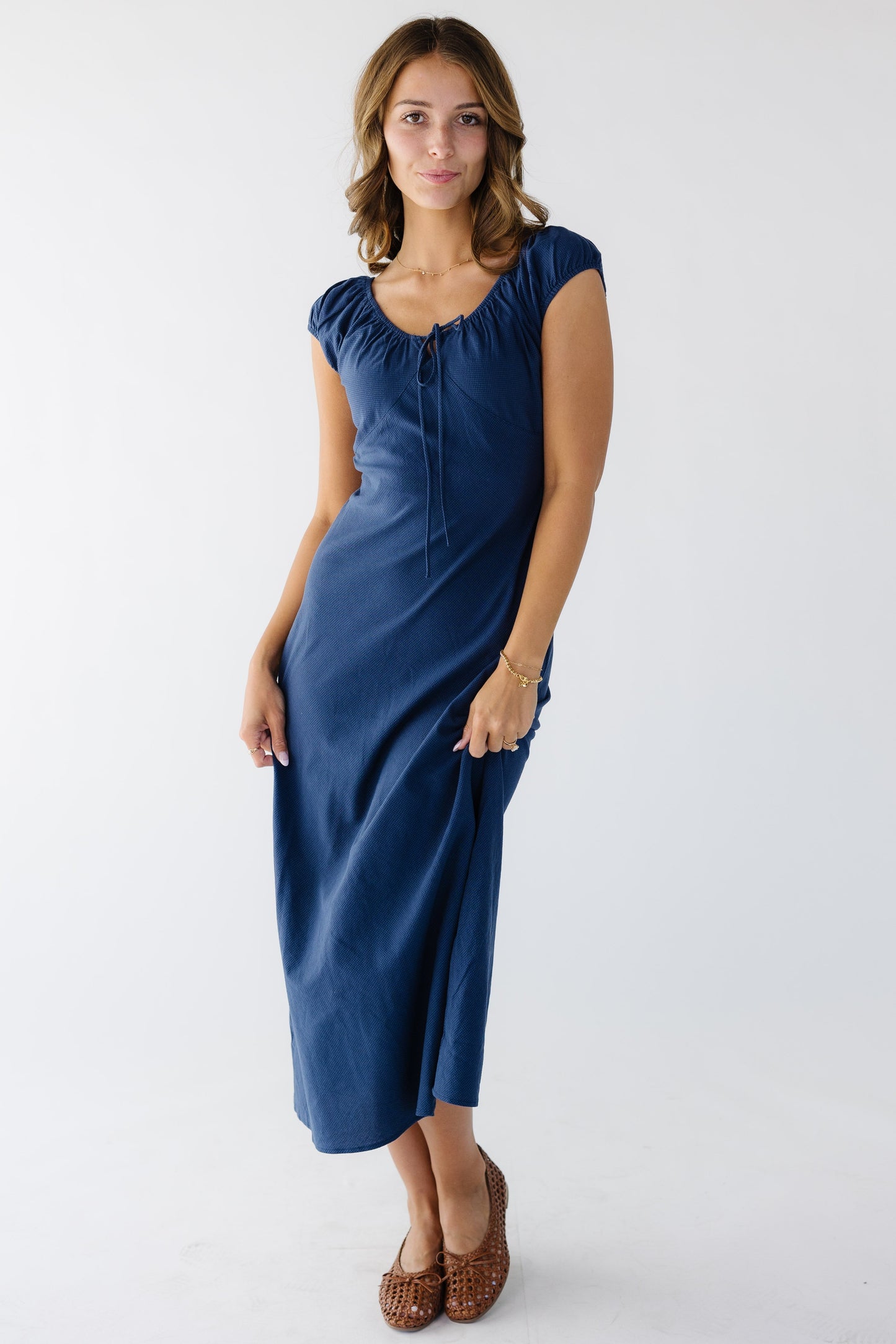 Young woman wearing a modest navy midi dress with a scoop neckline and short puff sleeves.