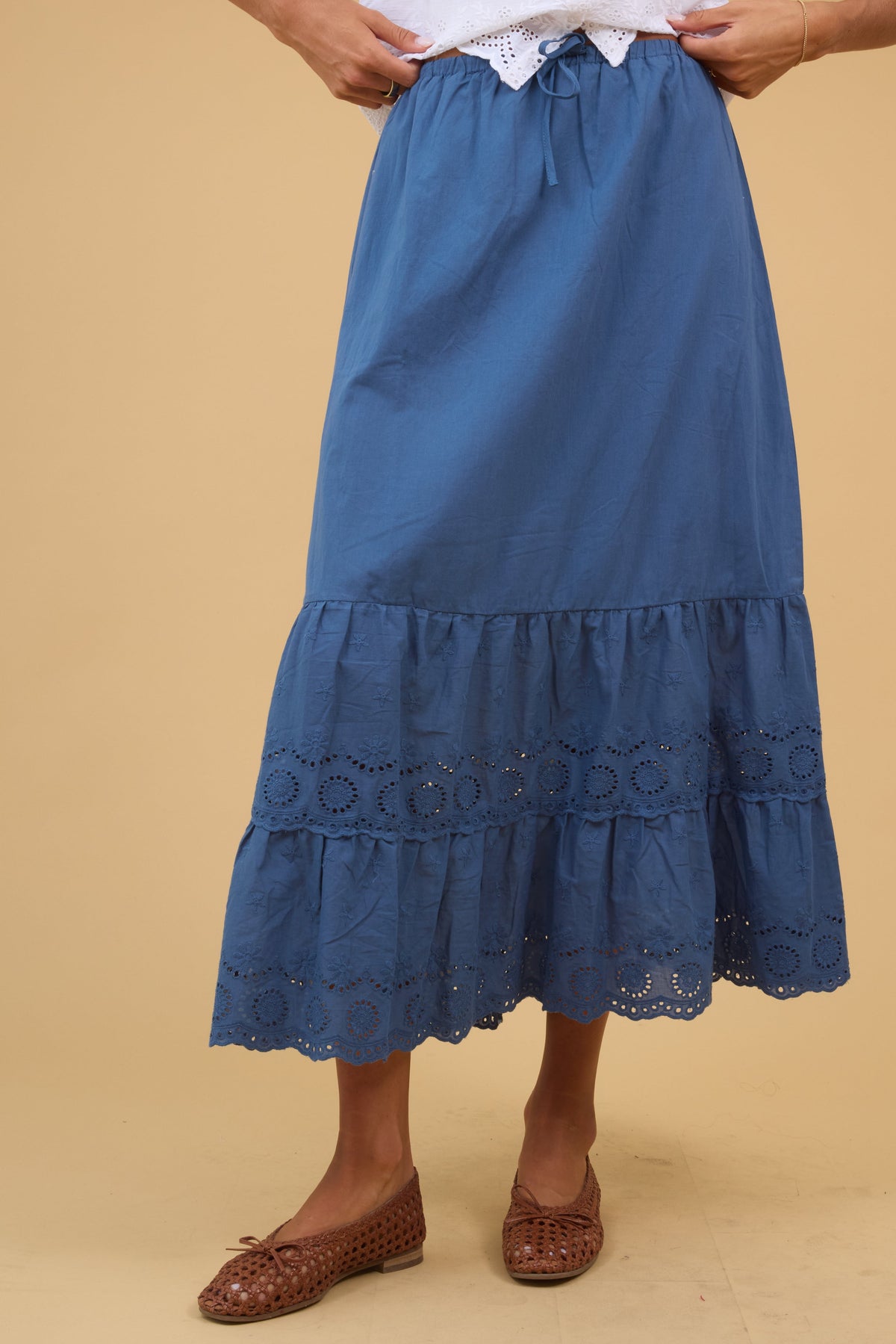 Young woman wearing a modest blue midi skirt with a double eyelet ruffle.