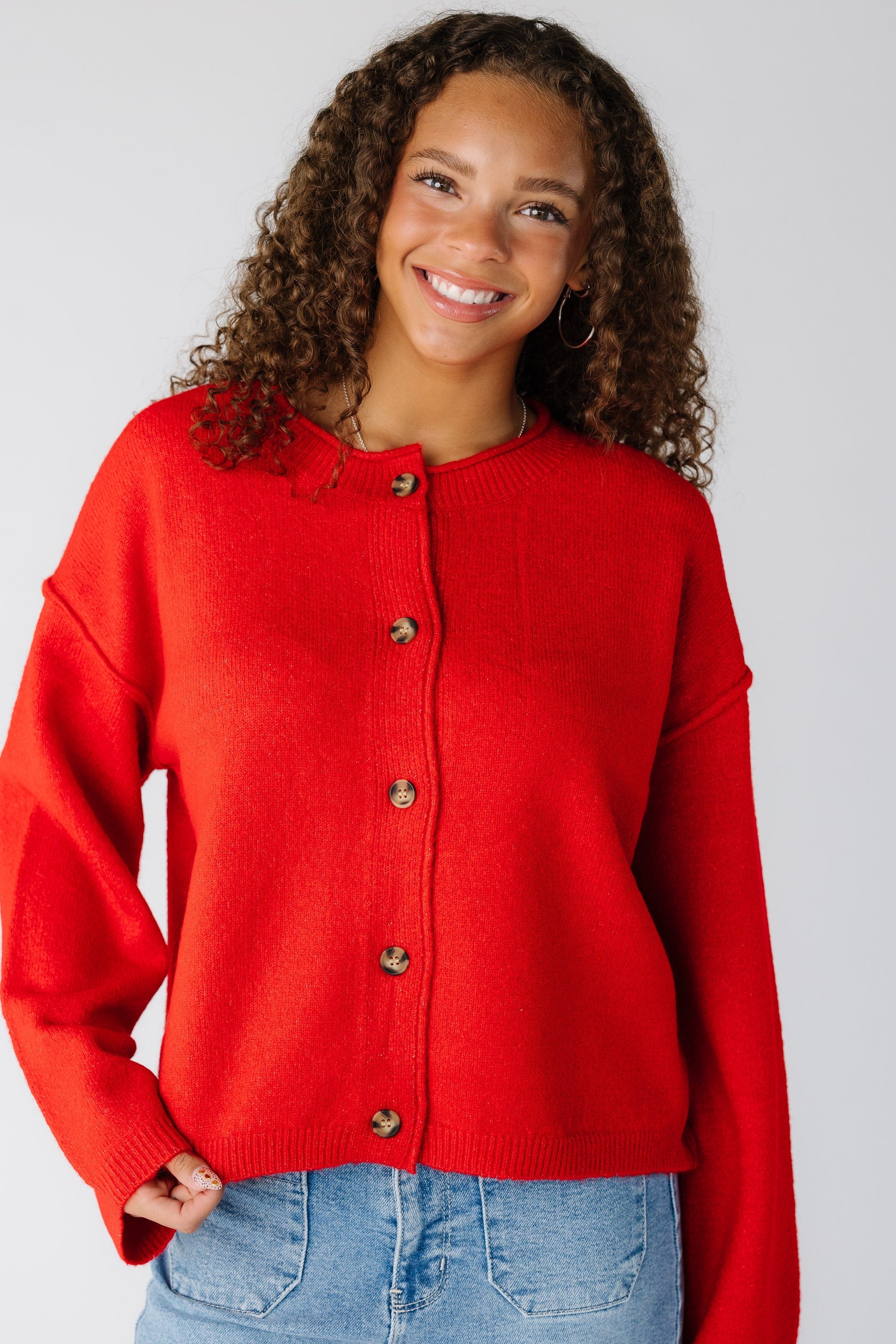 Woman wearing a modest red cardigan with a round neckline and long sleeves
