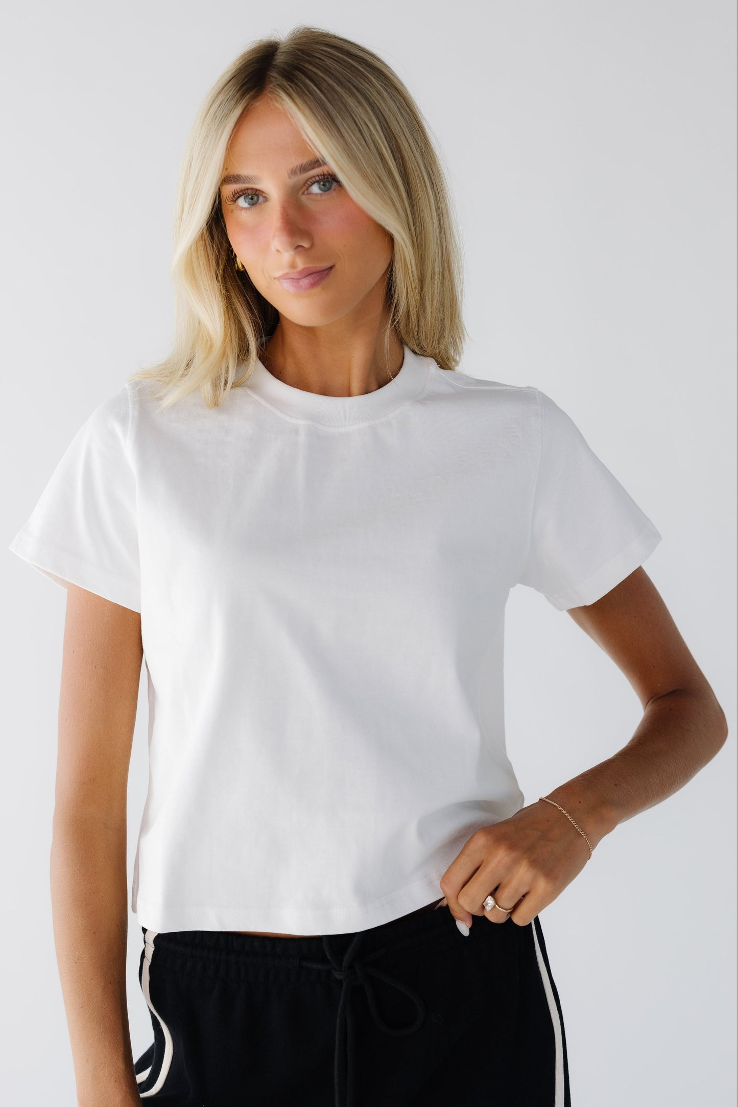 Young woman wearing a modest white tee with short sleeves and a wide crew neckline.