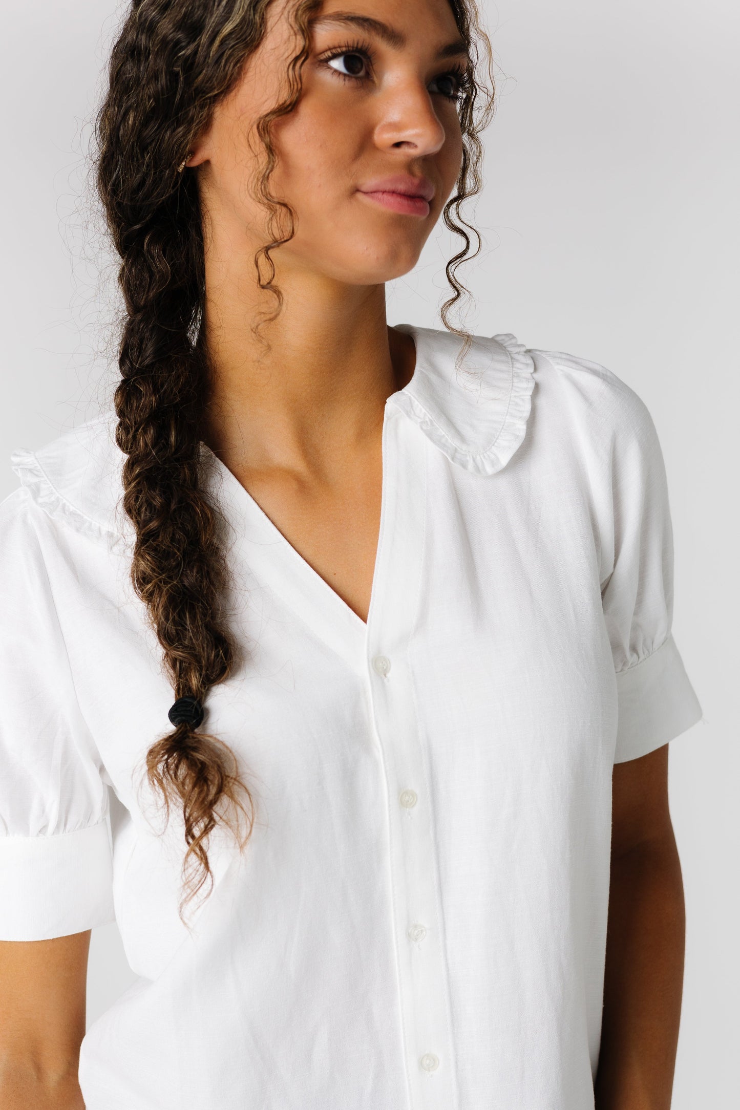 Close view of white top with V-neckline and collar with narrow edge ruffle