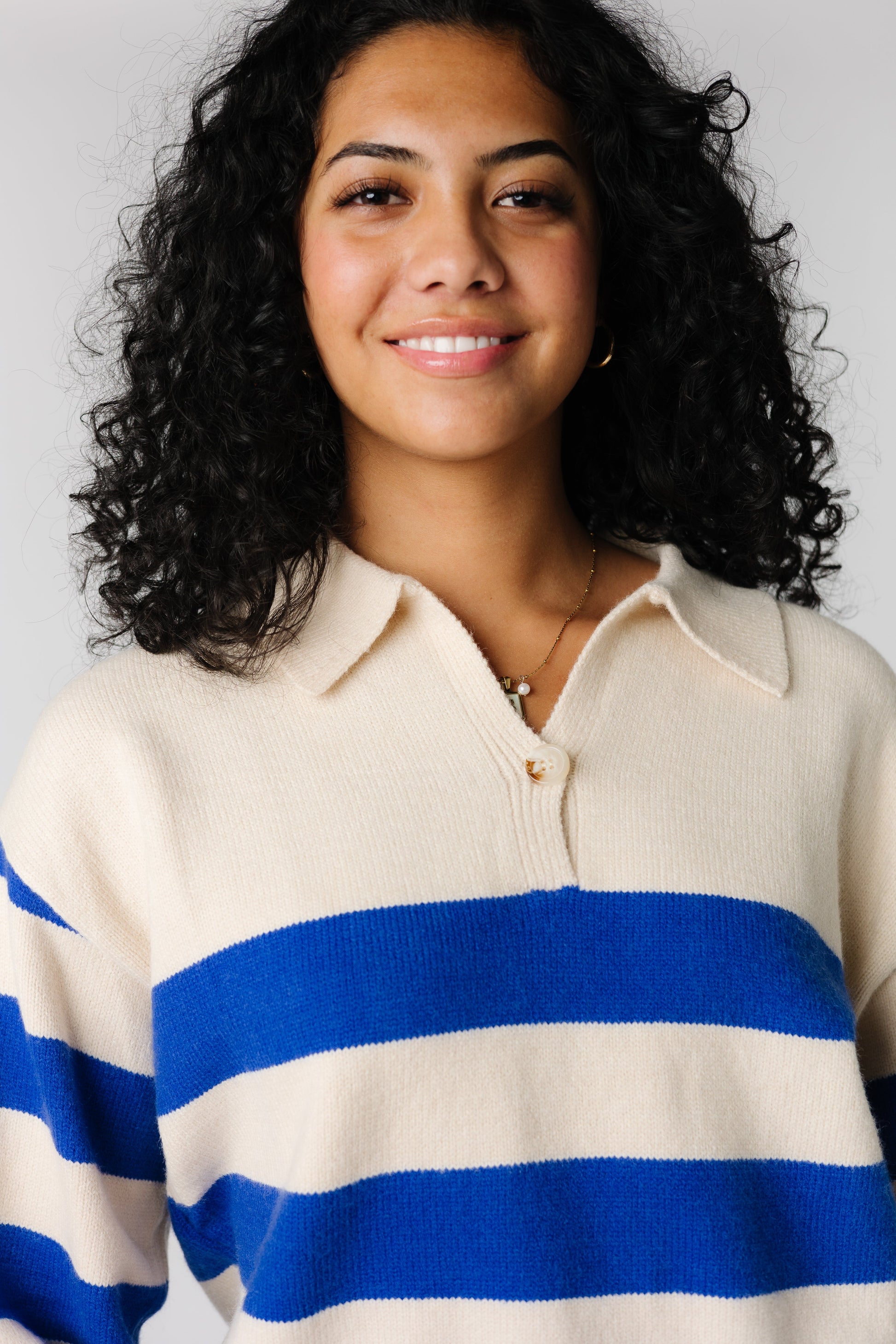 Close view of cream and blue wide stripe sweater with pointed collar and single button