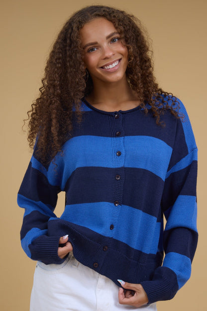 Young woman wearing a blue & navy wide stripe cardigan with long sleeves.