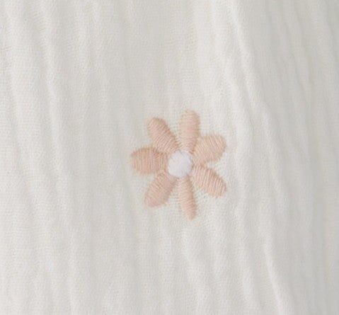 Fabric swatch of a pink flower on a crepe textured fabric swatch.