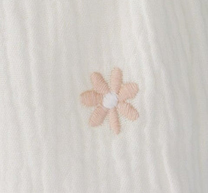 Fabric swatch of a pink flower on a crepe textured fabric swatch.