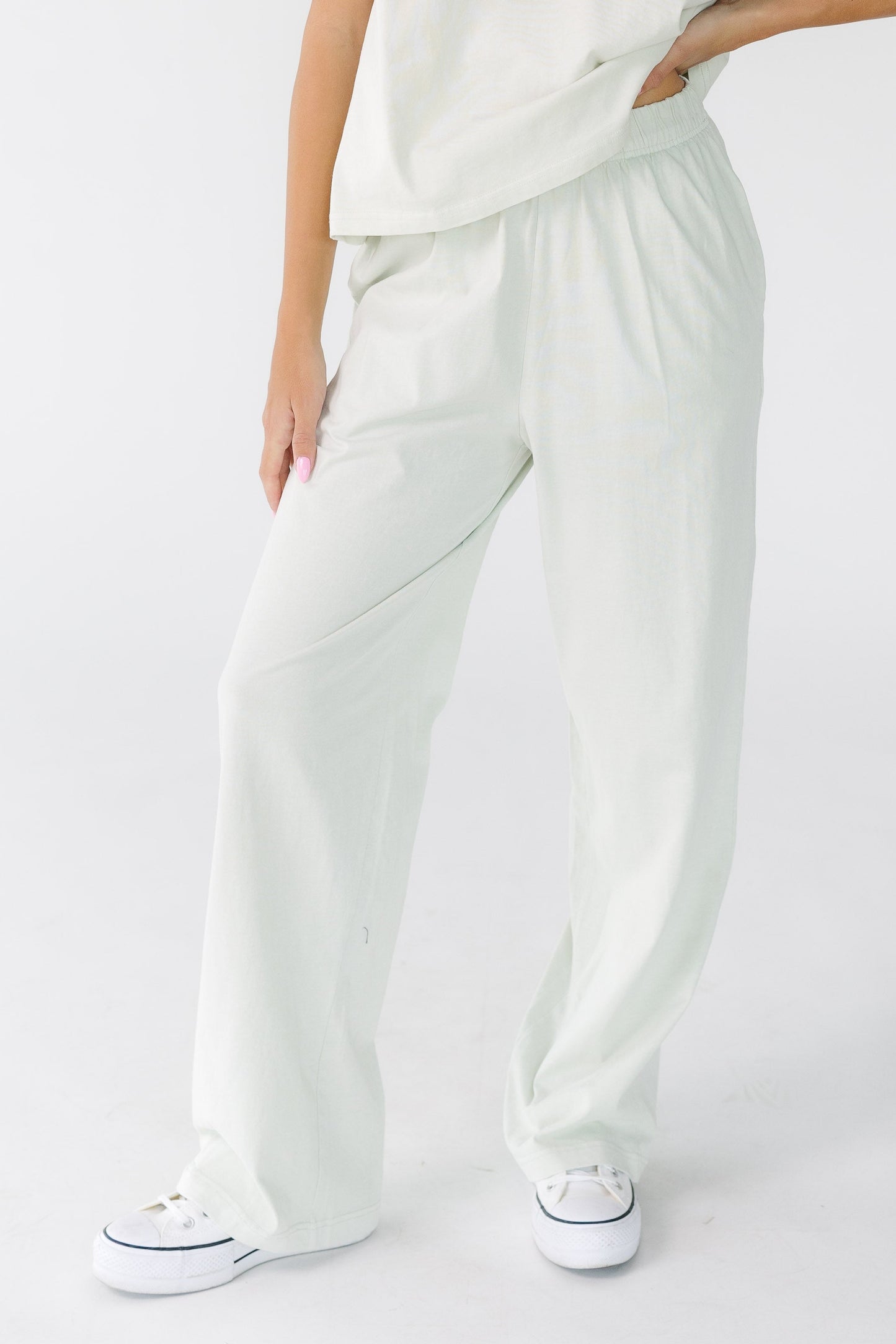 Young woman wearing a pair of wide leg pants with an elastic waist and side pockets.
