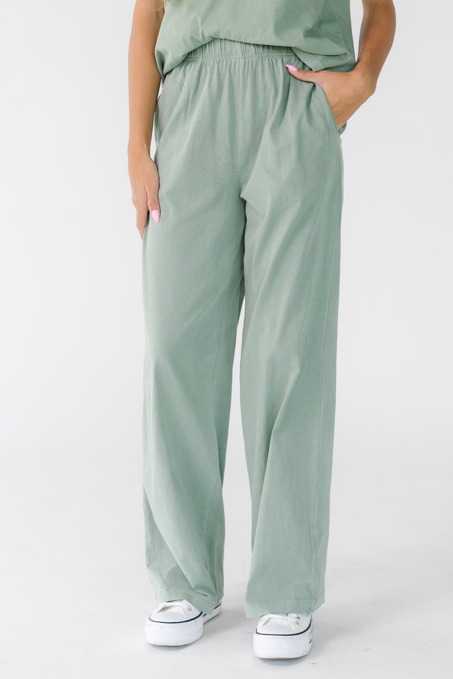 Young woman wearing a pair of sage green wide leg pants.