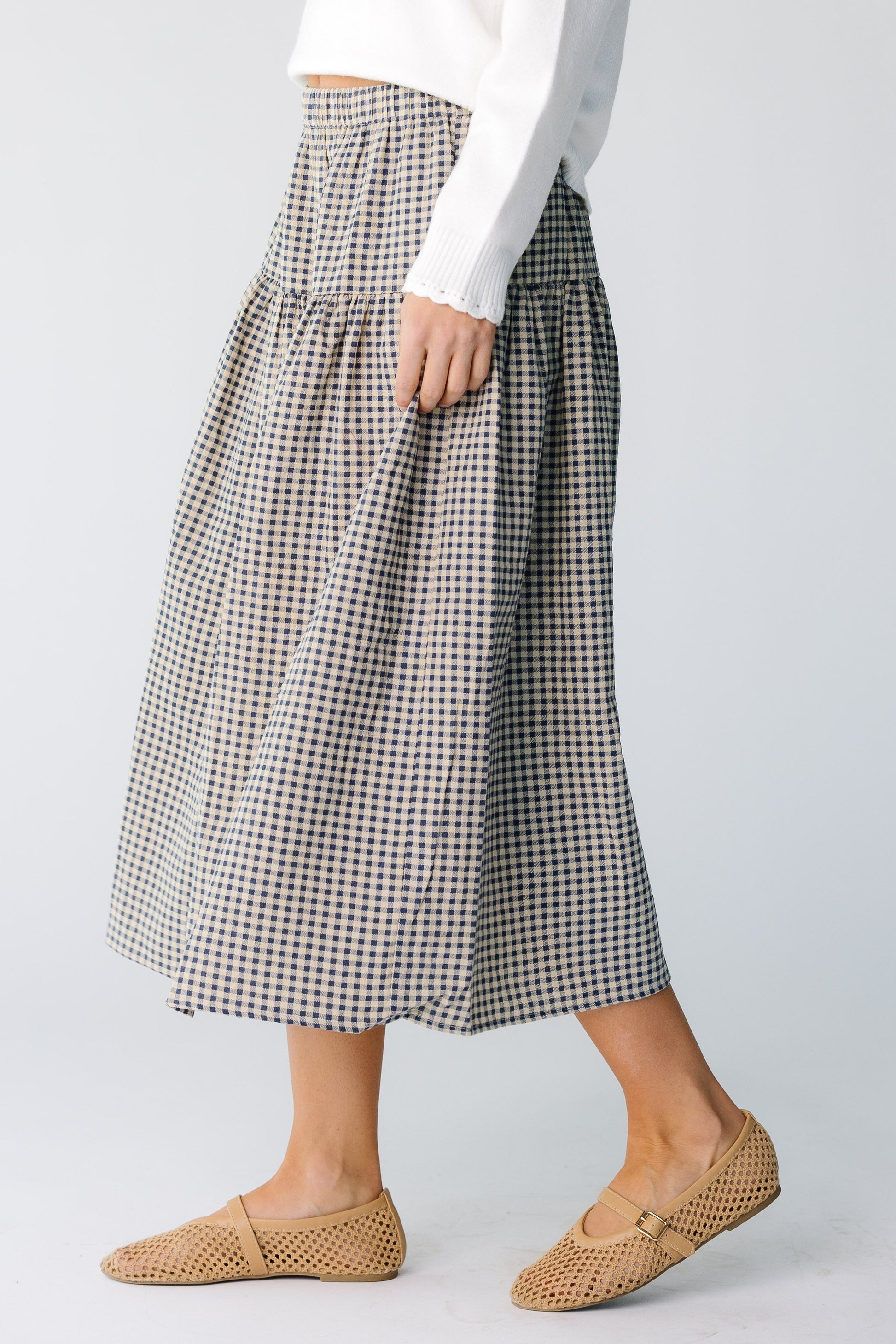 Side view of a woman wearing a navy gingham midi skirt