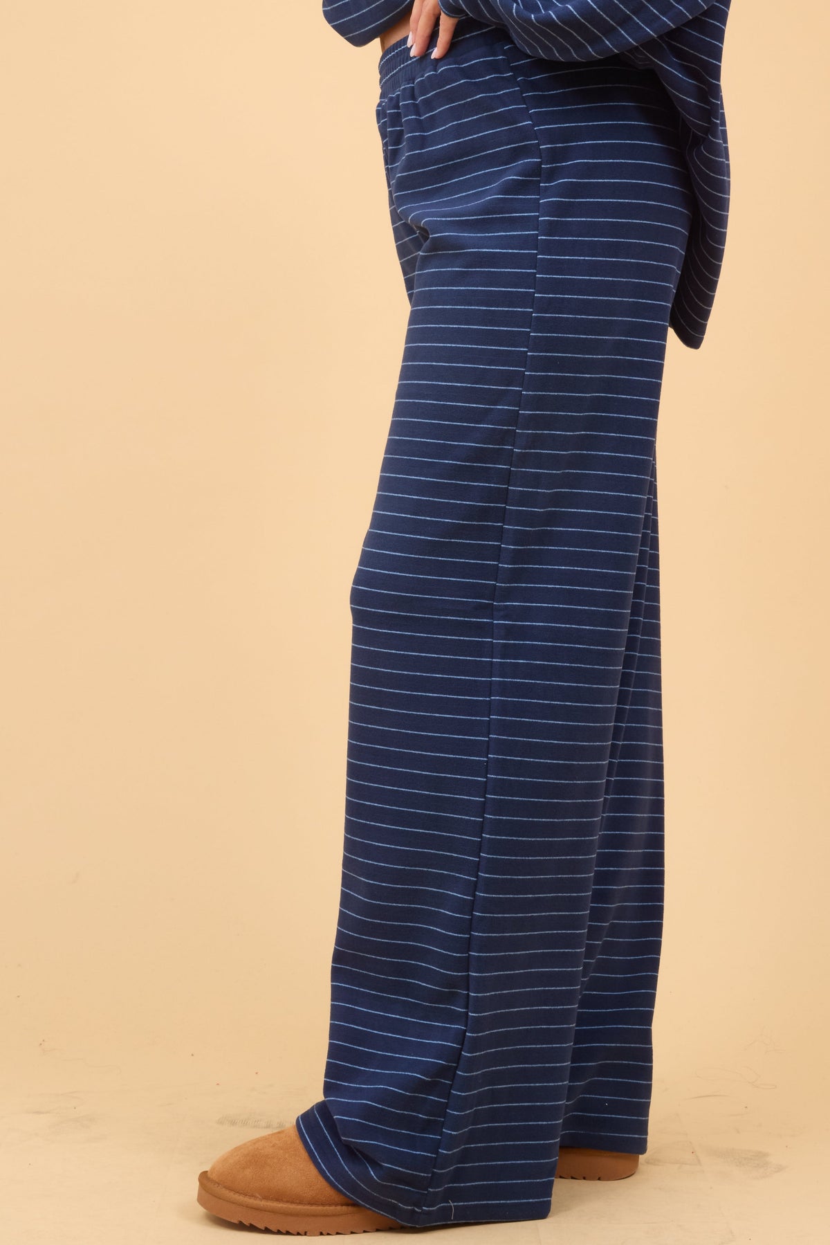 Side view of a woman wearing a navy stripe, wide cut lounge pant.