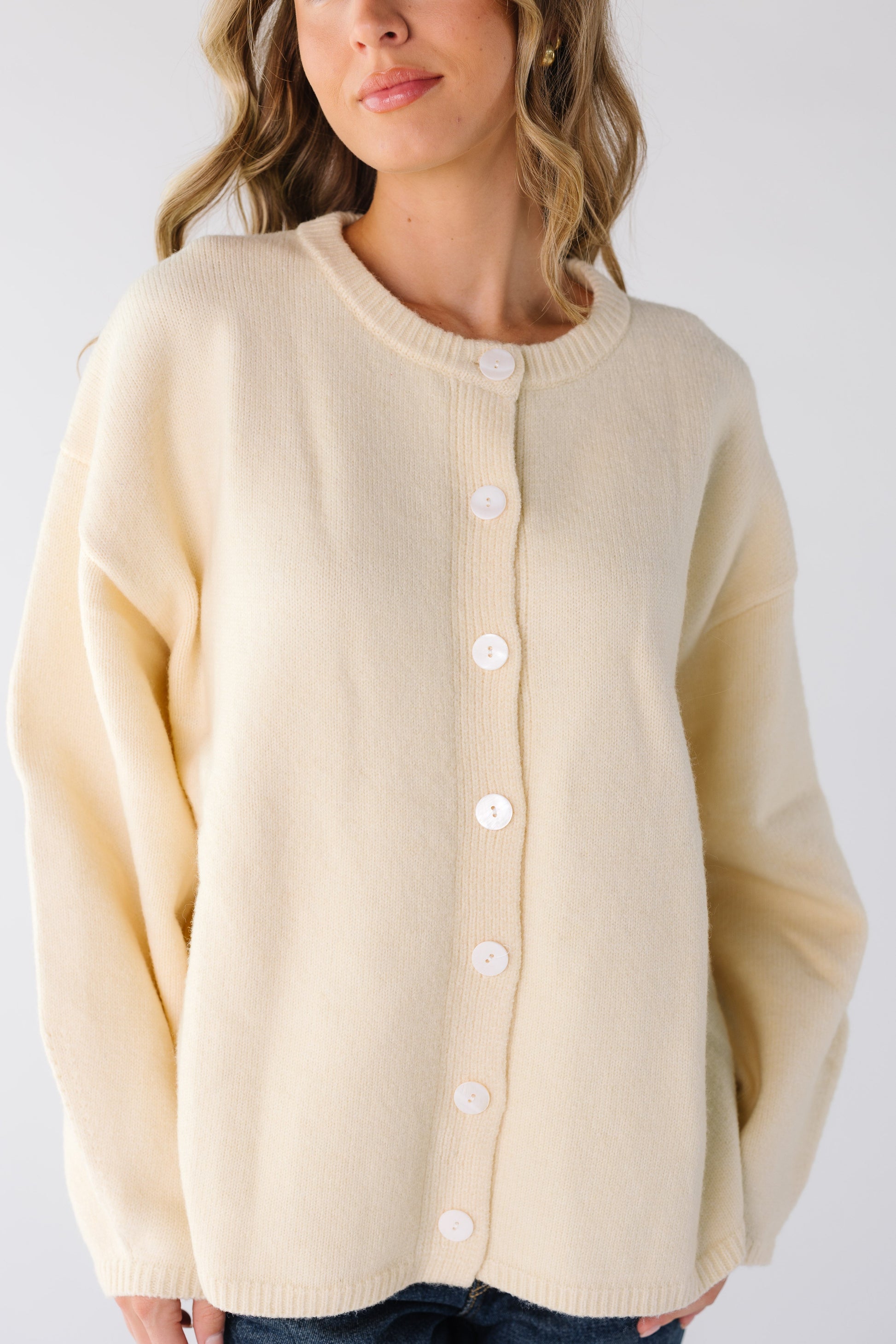 Close view of a woman wearing a cream button down cardigan with long sleeves