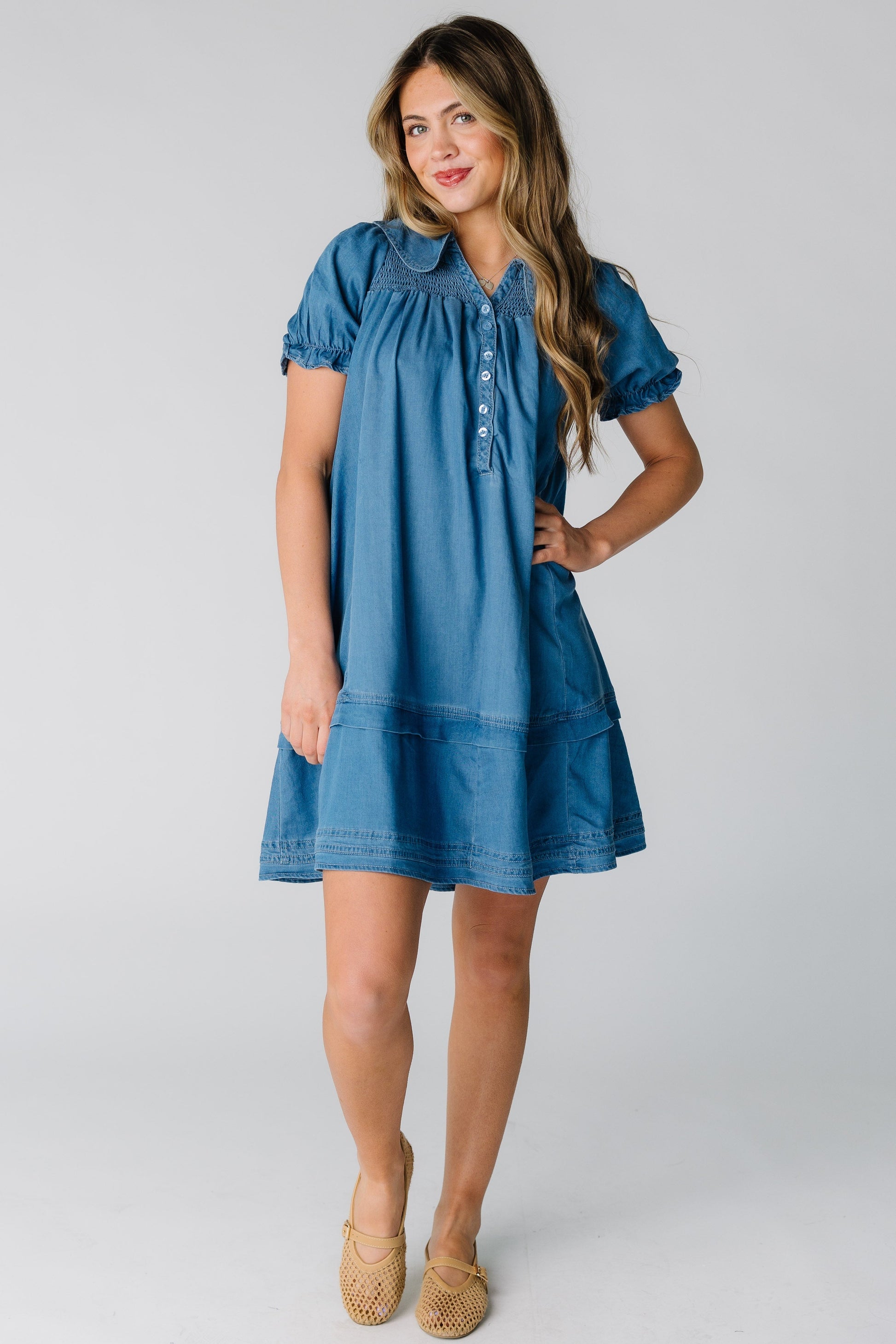 Woman wearing a loose fitting short dress in medium denim.