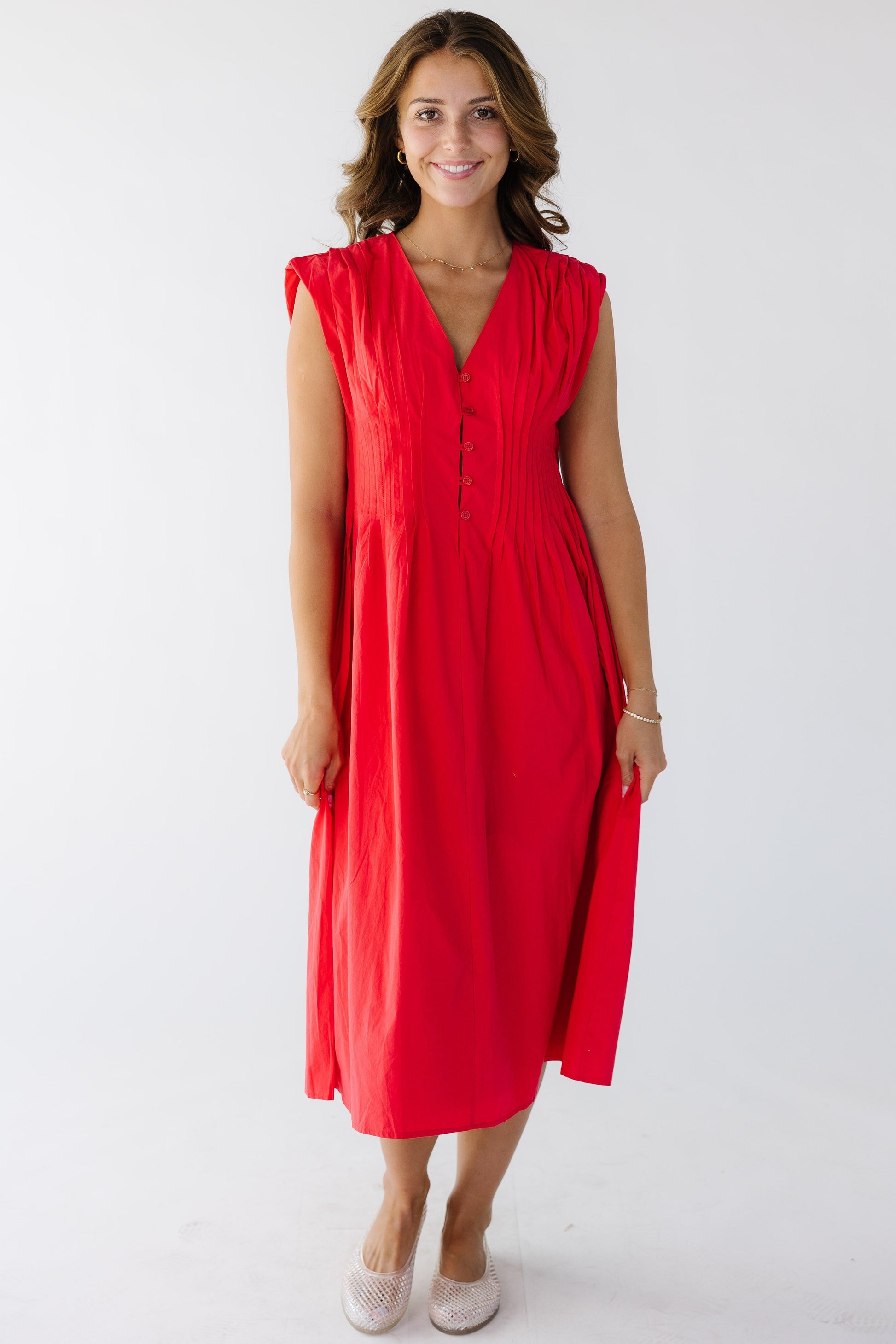 Woman wearing a red midi dress with an hour glass silhouette and a V-neckline.
