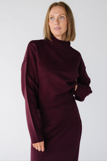 Close view of a woman wearing a dark cherry textured sweater and skirt set