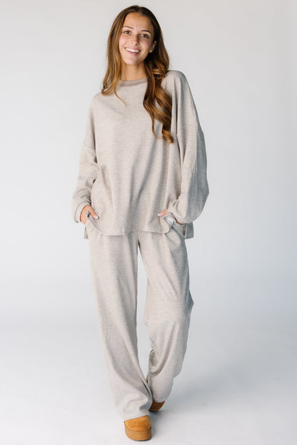 Woman wearing a modest 2 piece lounge set in a narrow taupe and white stripe with long sleeves and long length pants.