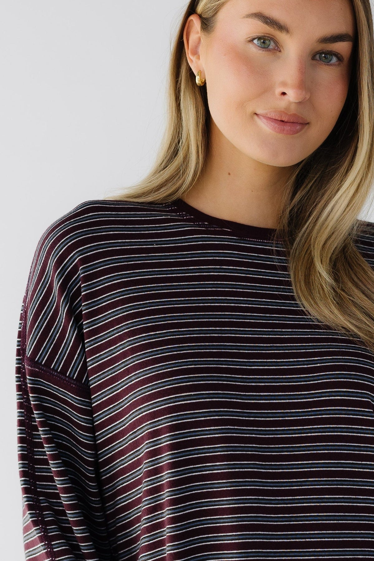 A close view of a woman wearing a loose fitting long sleeve tee with exposed seam details.