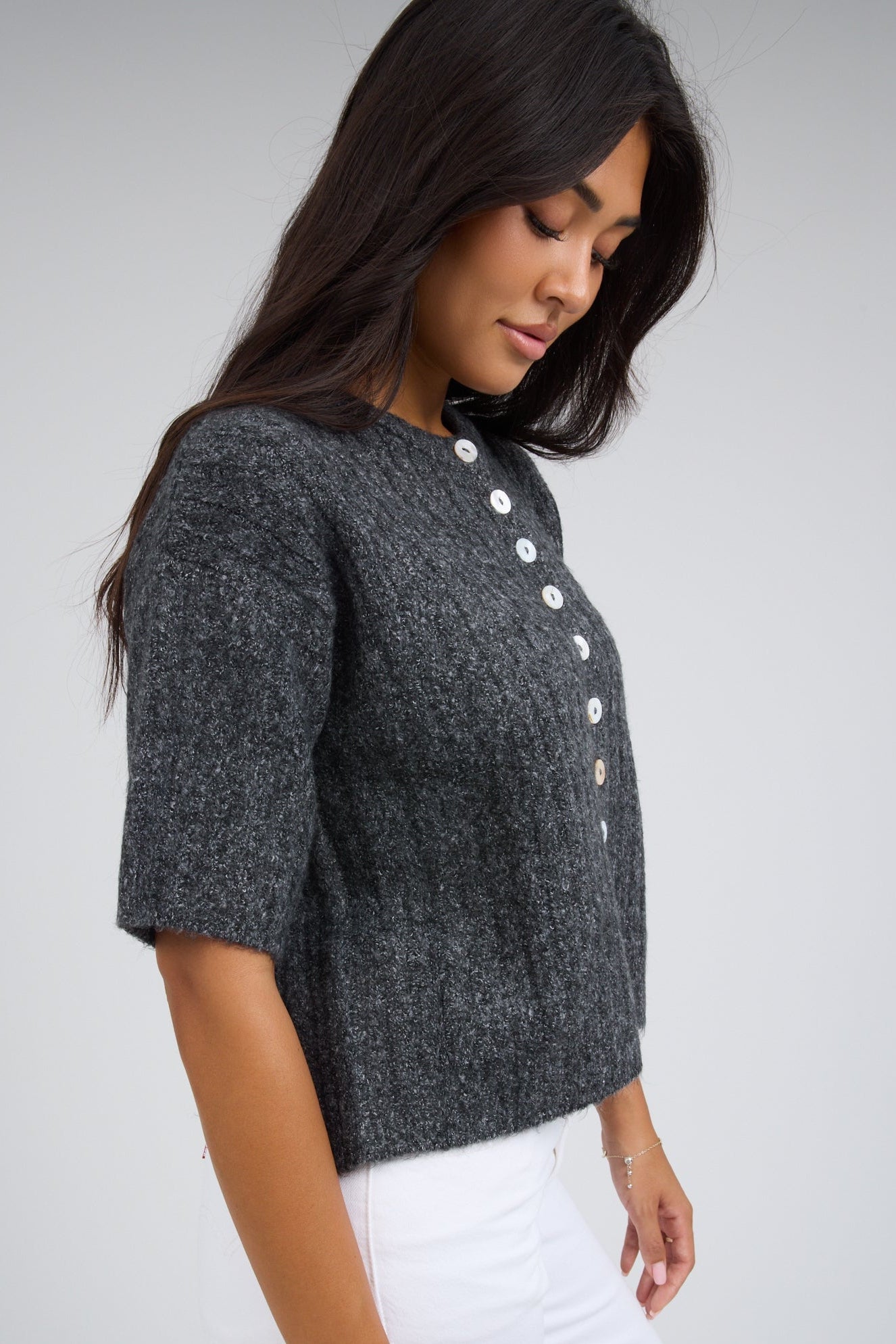 Woman wearing a charcoal grey button down cardigan with short sleeves.