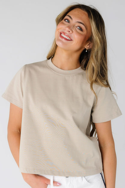 Young woman wearing a beige short sleeve with a crew neckline.
