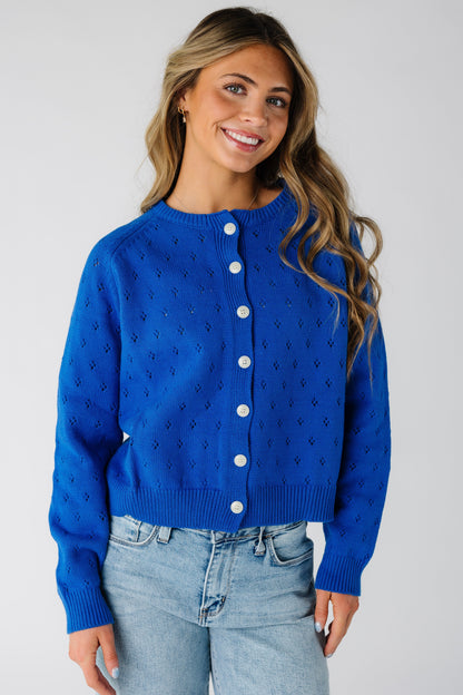 Woman wearing a button down cardigan with contrasting light color buttons and long sleeves.