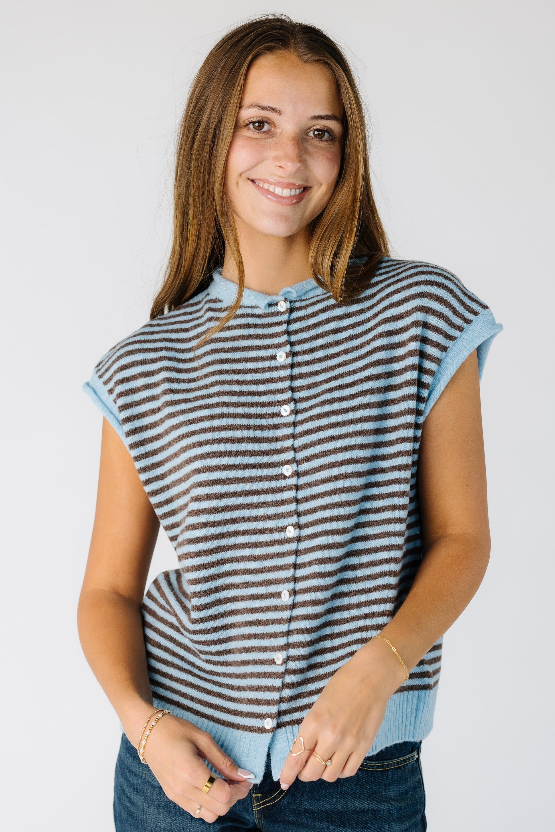Woman wearing a modest button down sweater vest in light blue and brown stripe.