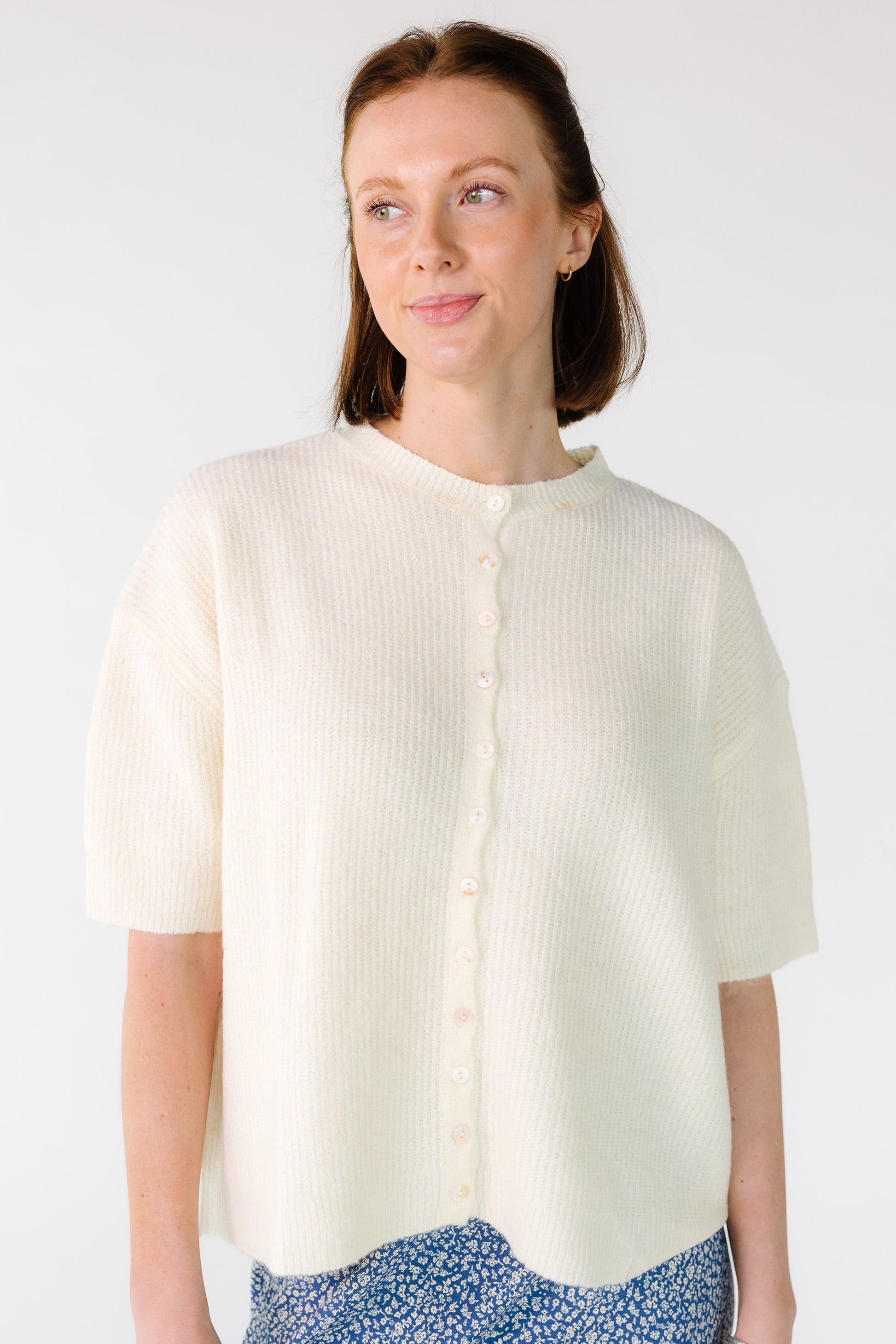Woman wearing a modest loose fitting button down cardigan with short sleeves.
