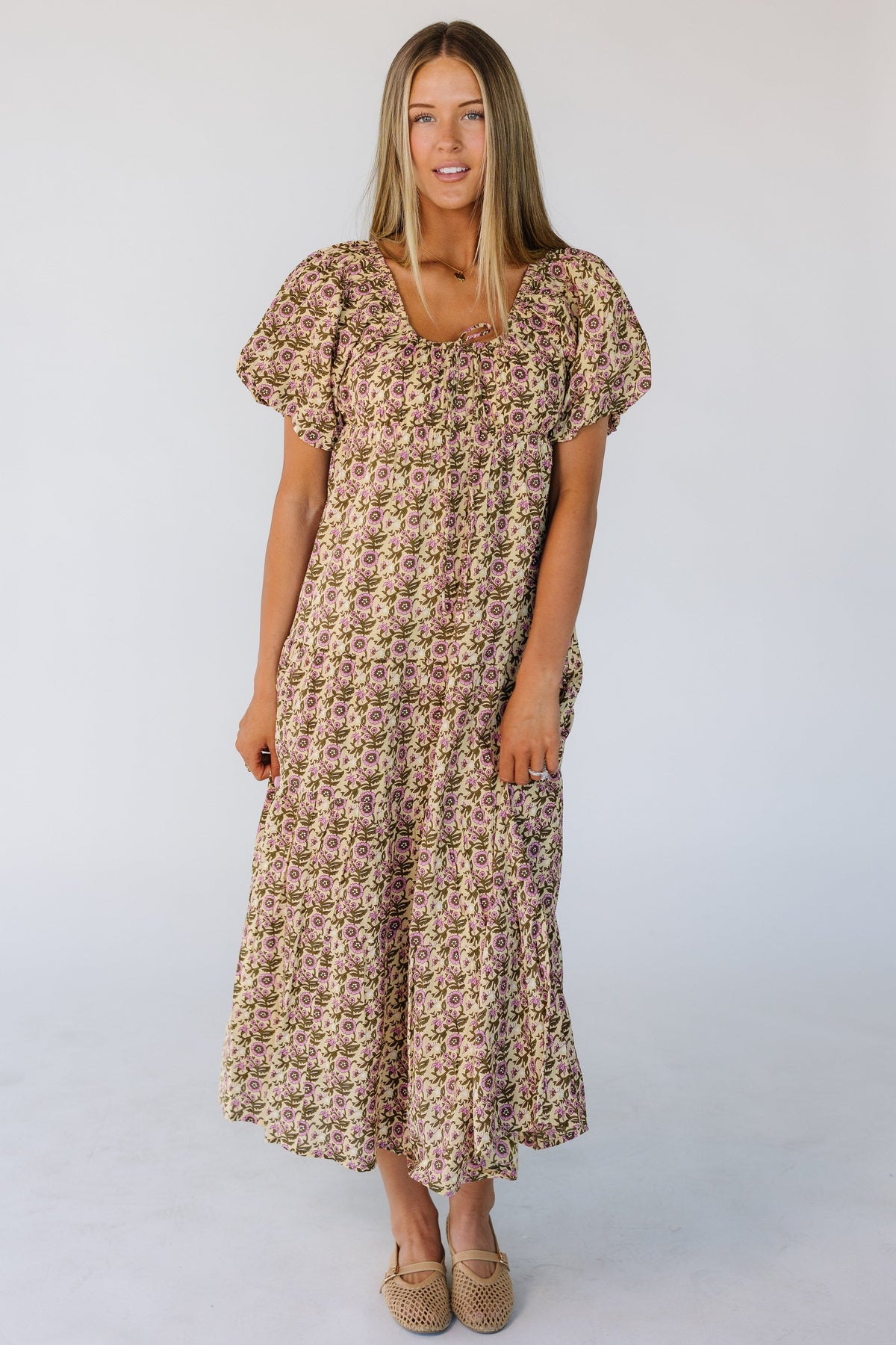 Young woman wearing a modest floral print dress in a green & pink floral midi dress with a drawstring scoop neckline, large puff sleeves and full skirt.