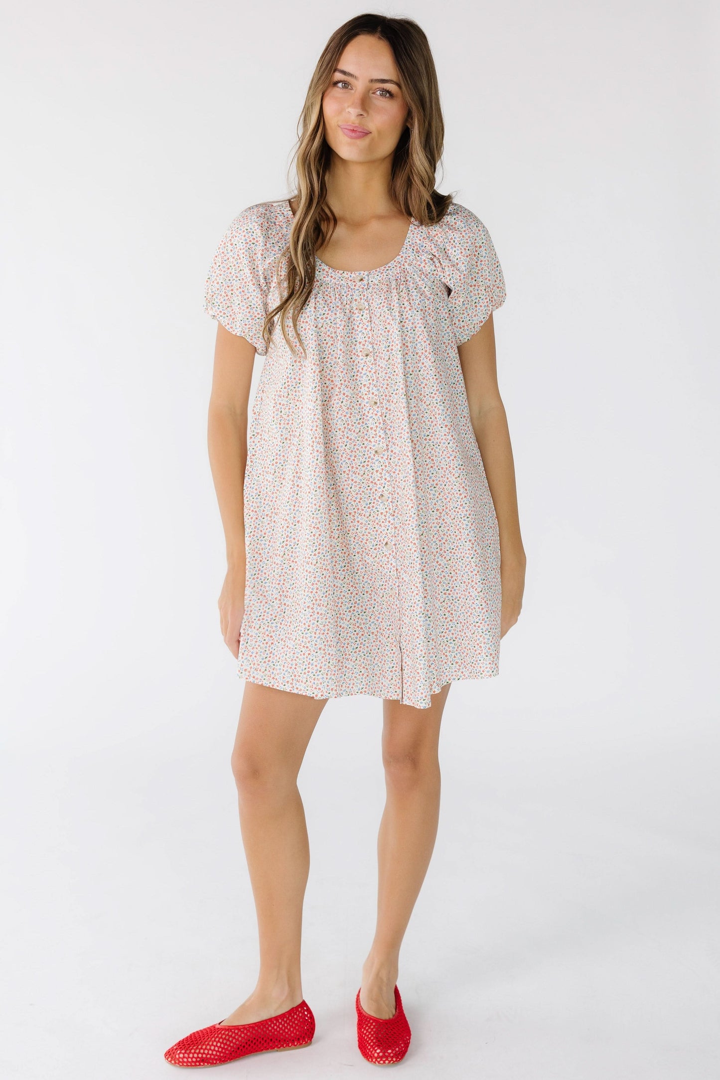 Woman wearing a modest above the knee loose fitting swing dress that buttons down the front.