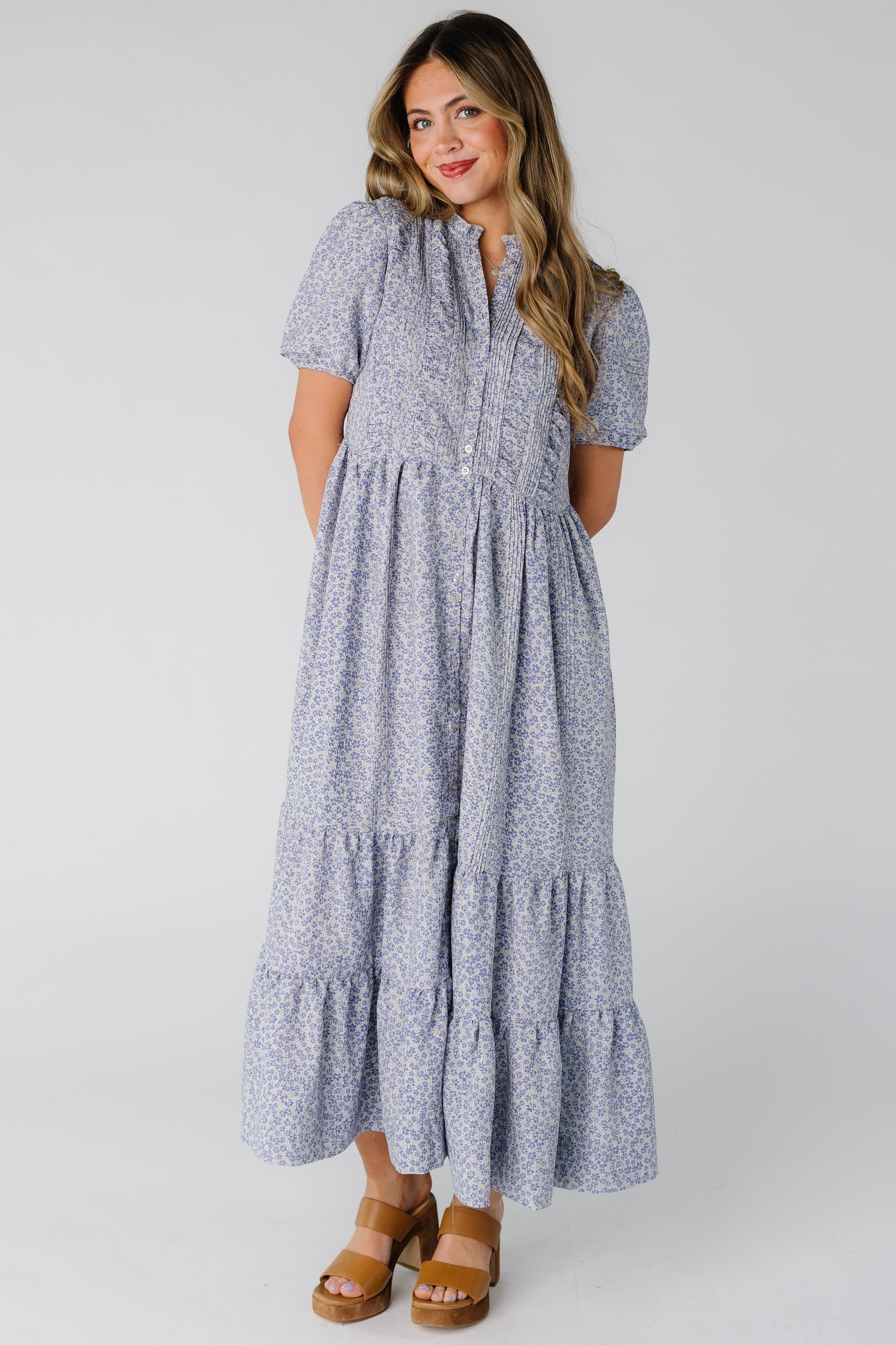 A woman wearing a modest purple floral midi dress with a round neckline and short sleeves.