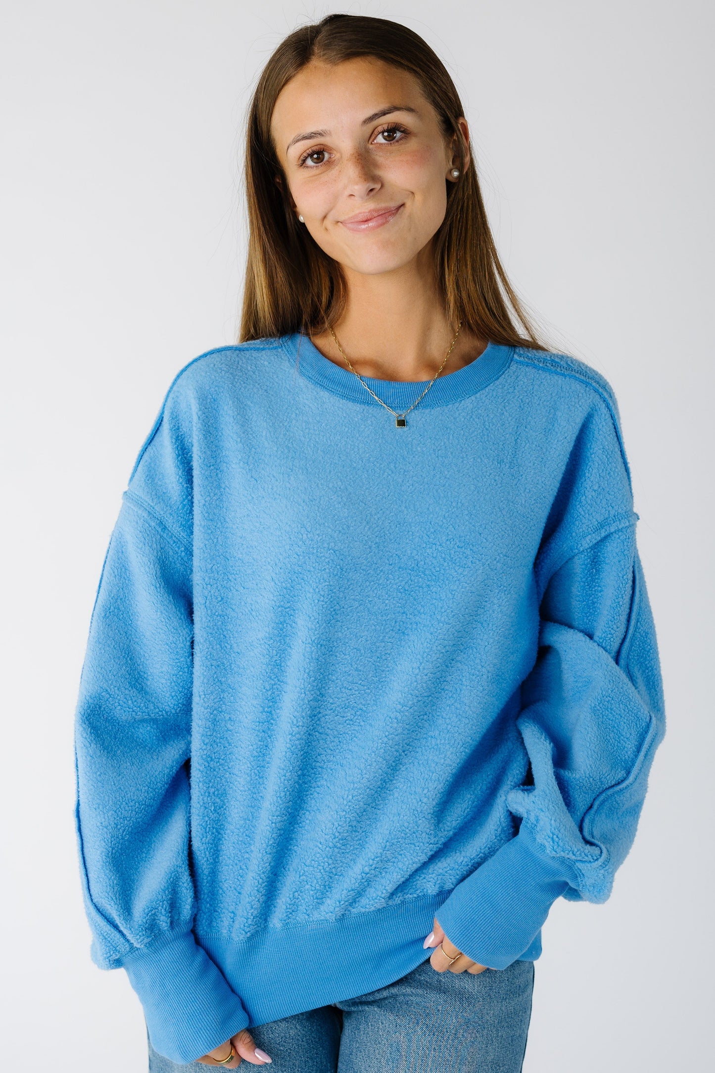 Woman wearing a blue loose fitting sweater-sweatshirt with long sleeves with wide ribbed cuffs