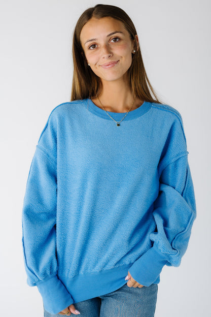 Woman wearing a blue loose fitting sweater-sweatshirt with long sleeves with wide ribbed cuffs