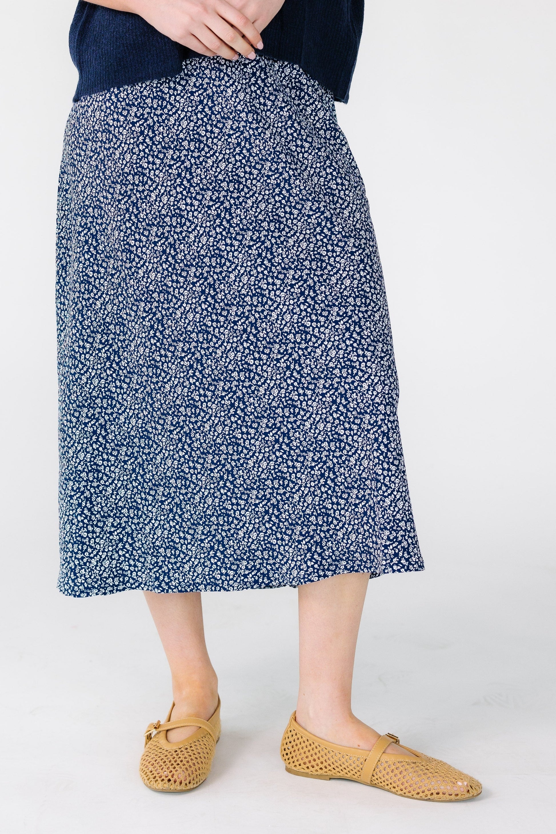 Close view of a woman wearing a pair of navy and white floral midi skirt.