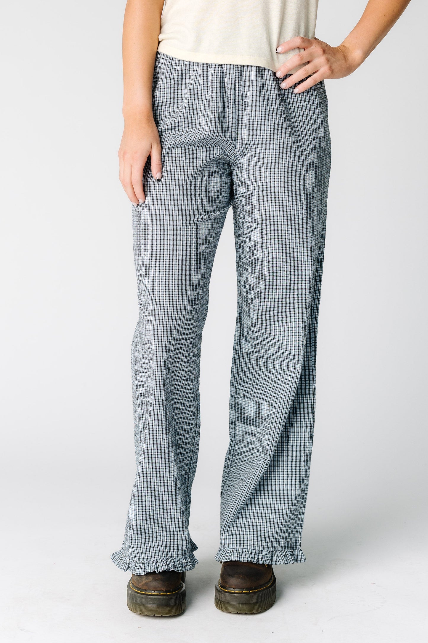 Woman wearing a pair of slightly loose fitting plaid pants in blue with a ruffle hem