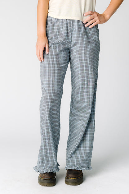 Woman wearing a pair of slightly loose fitting plaid pants in blue with a ruffle hem