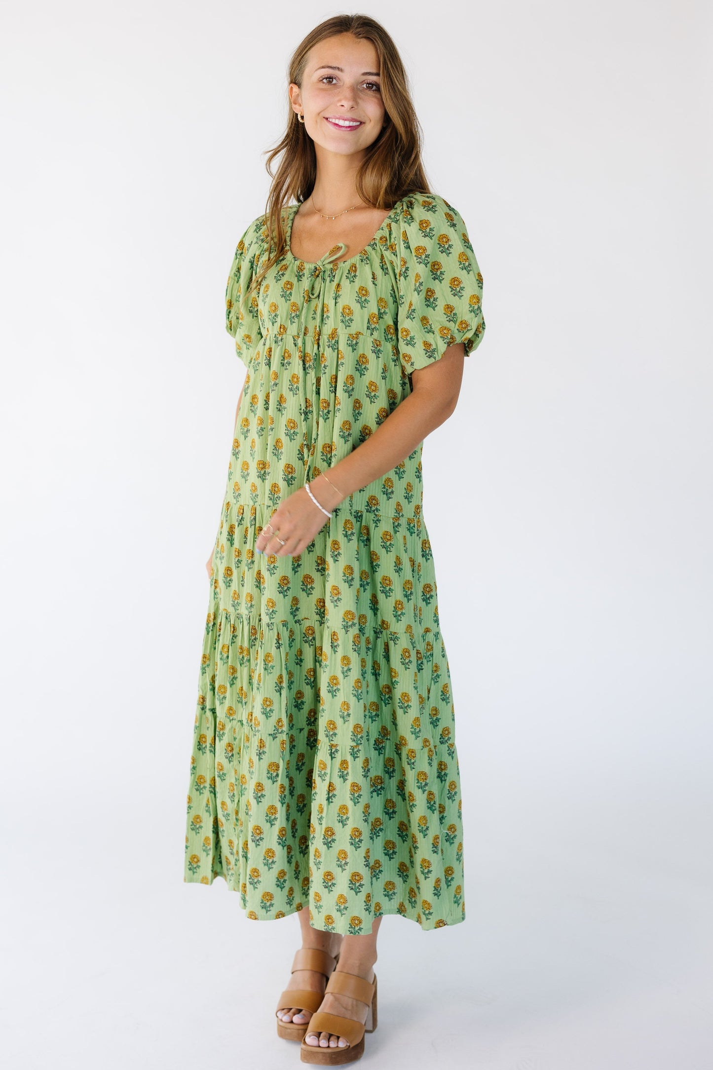 Woman wearing a modest green floral print midi dress with a drawstring-scoop neckline and short balloon sleeves.