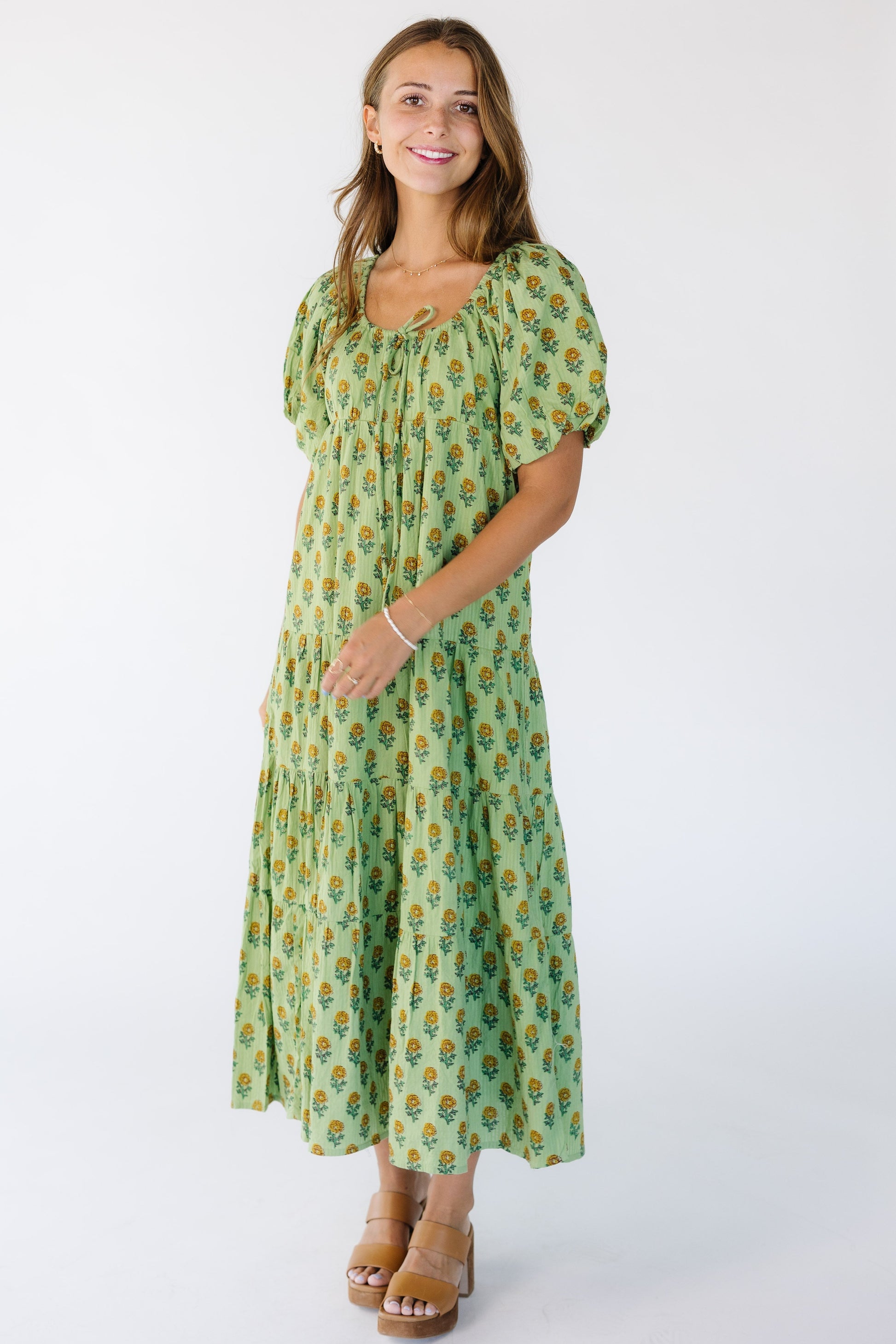 Woman wearing a modest green floral print midi dress with a drawstring-scoop neckline and short balloon sleeves.
