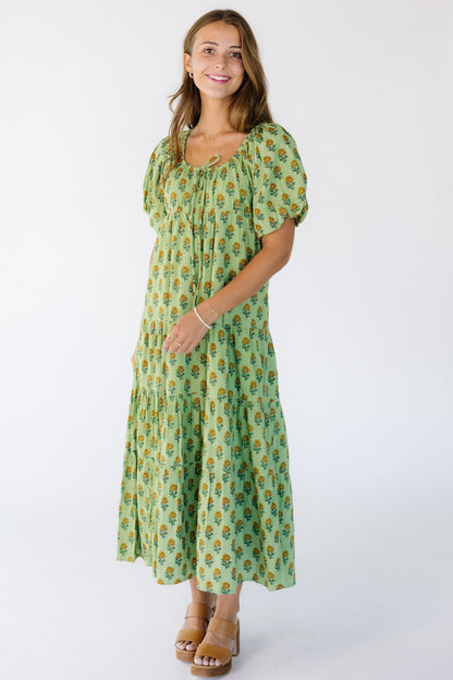 Woman wearing a modest green floral print midi dress with a drawstring-scoop neckline and short balloon sleeves.