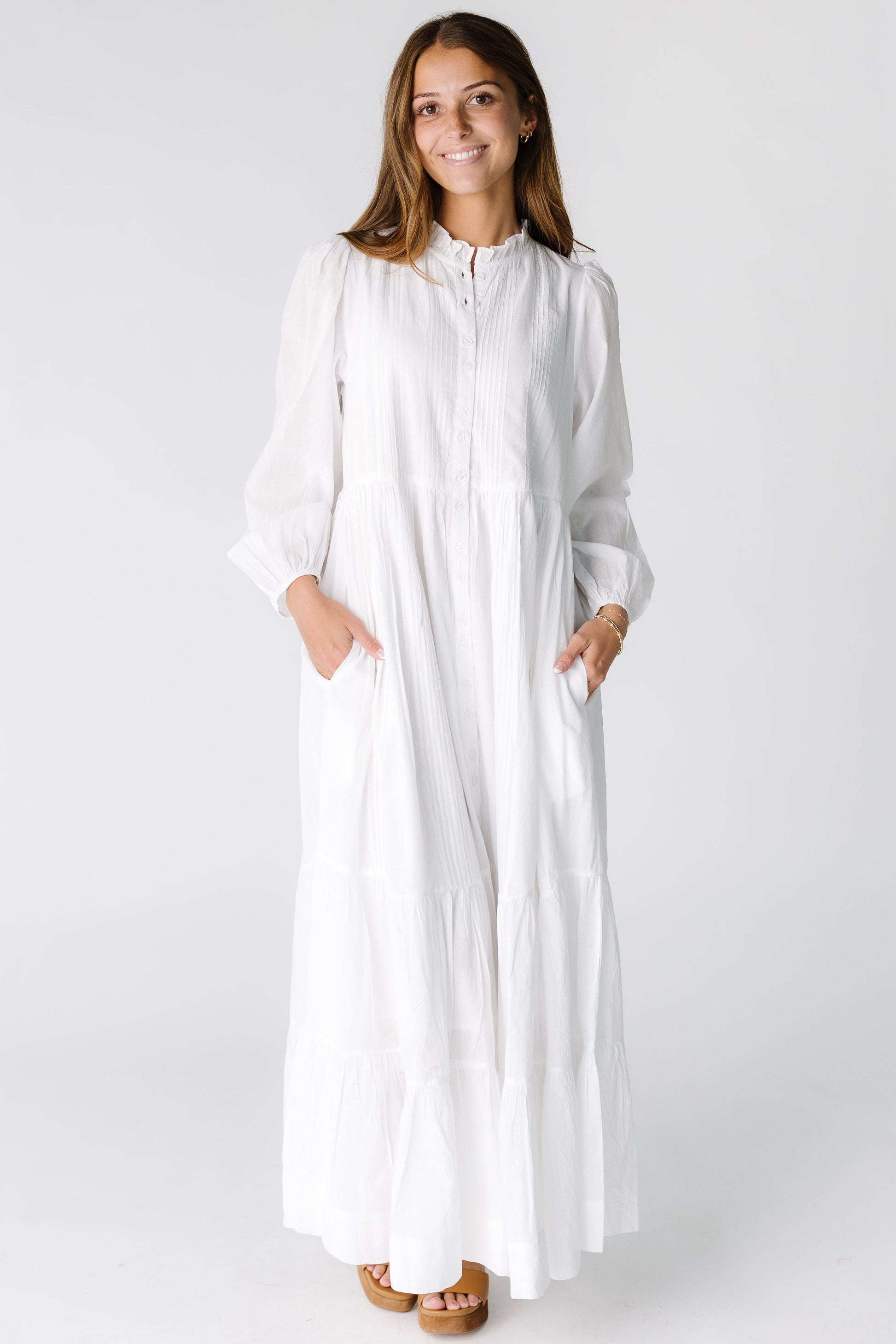 Woman wearing a white long sleeve maxi dress with a round collar and pockets