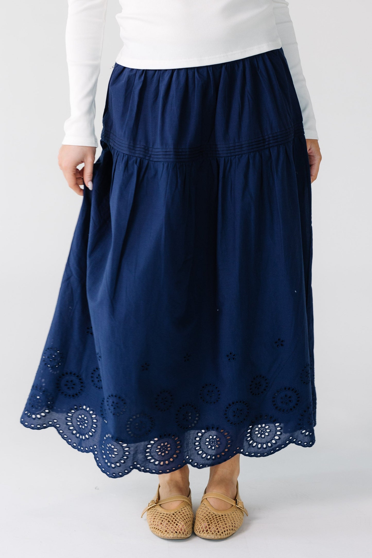 Woman wearing a modest navy midi skirt with a bottom eyelet border detail.