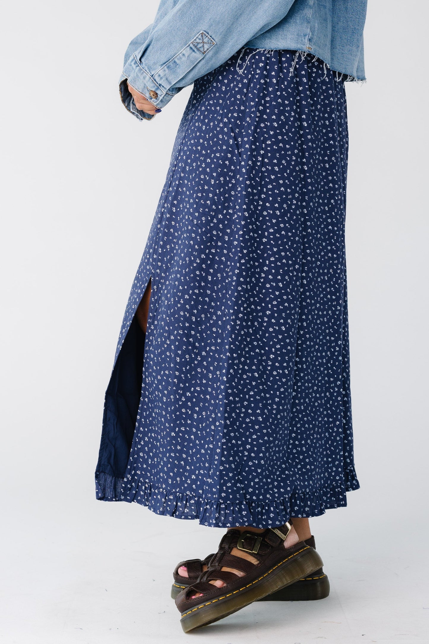 Side view of a woman wearing a navy floral skirt with front slit