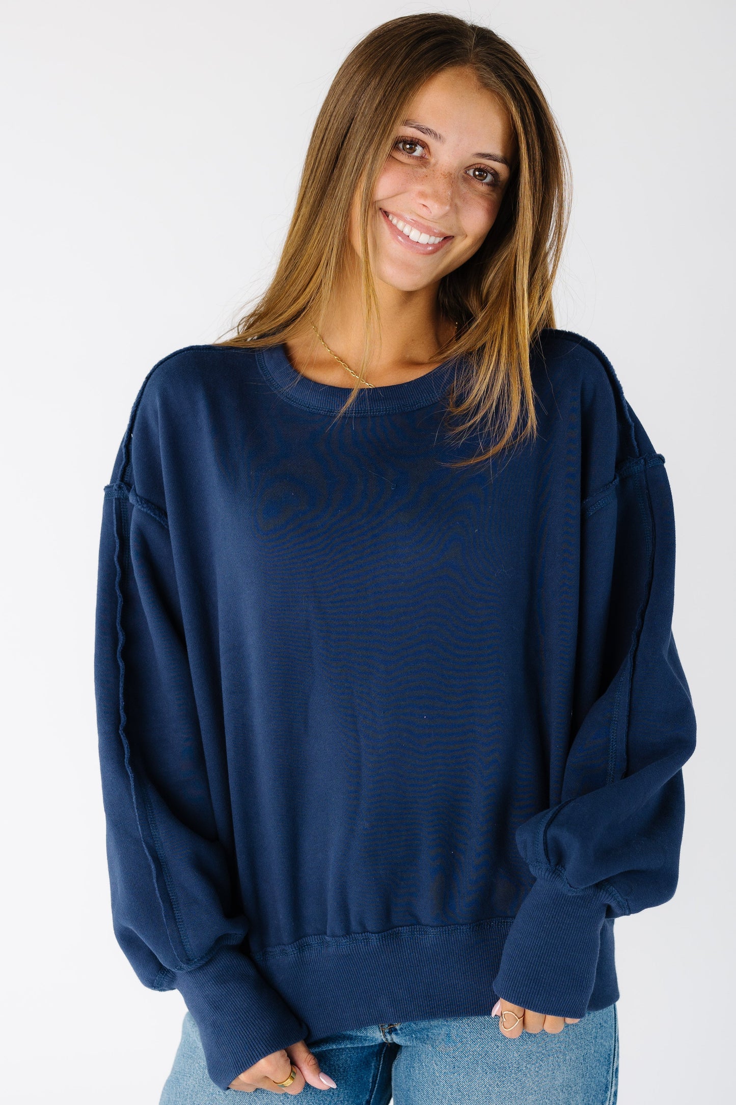 Woman wearing a navy reversible sweatshirt with wide ribbed cuffs