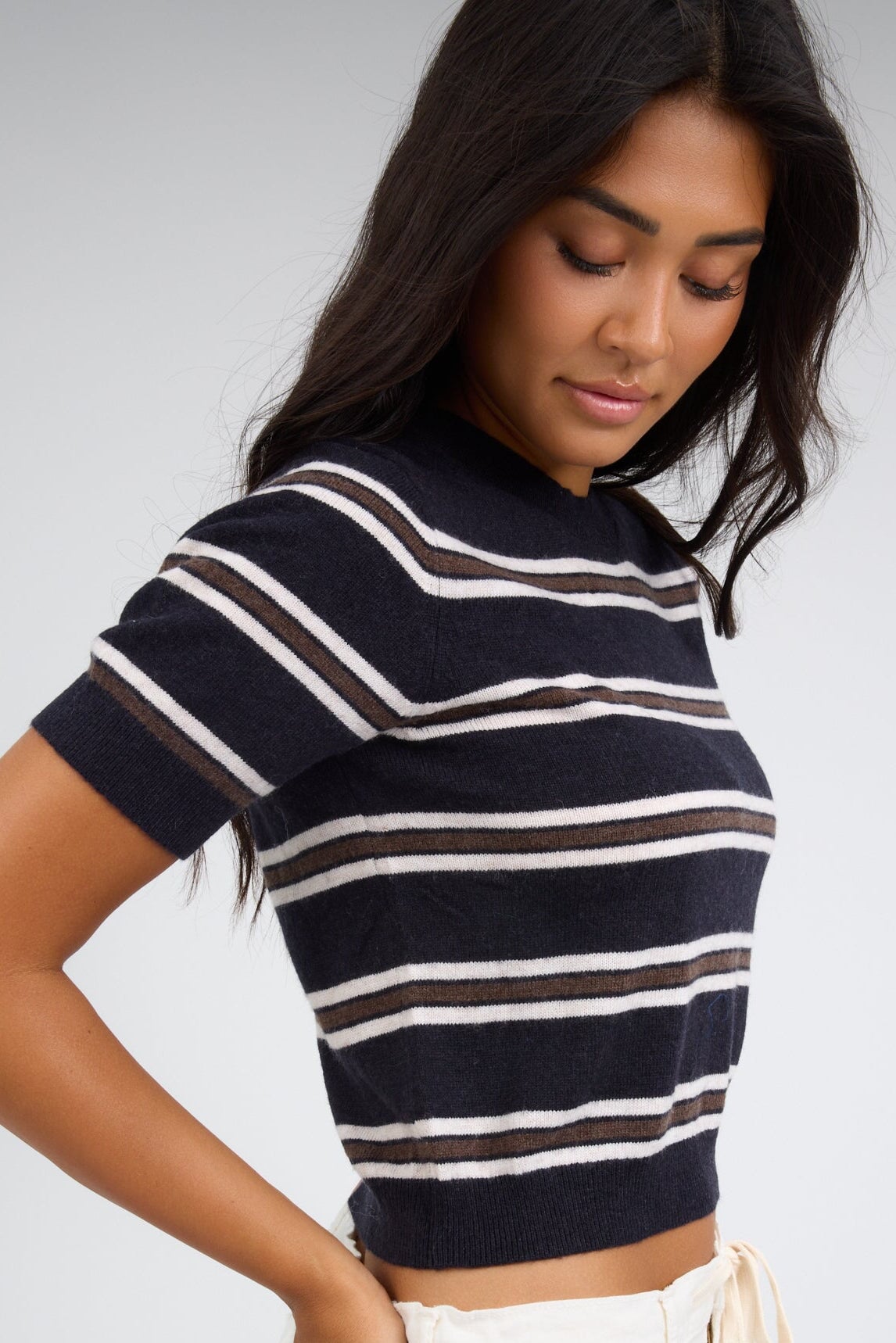 Side view of a woman wearing a navy brown and white stripe sweater.