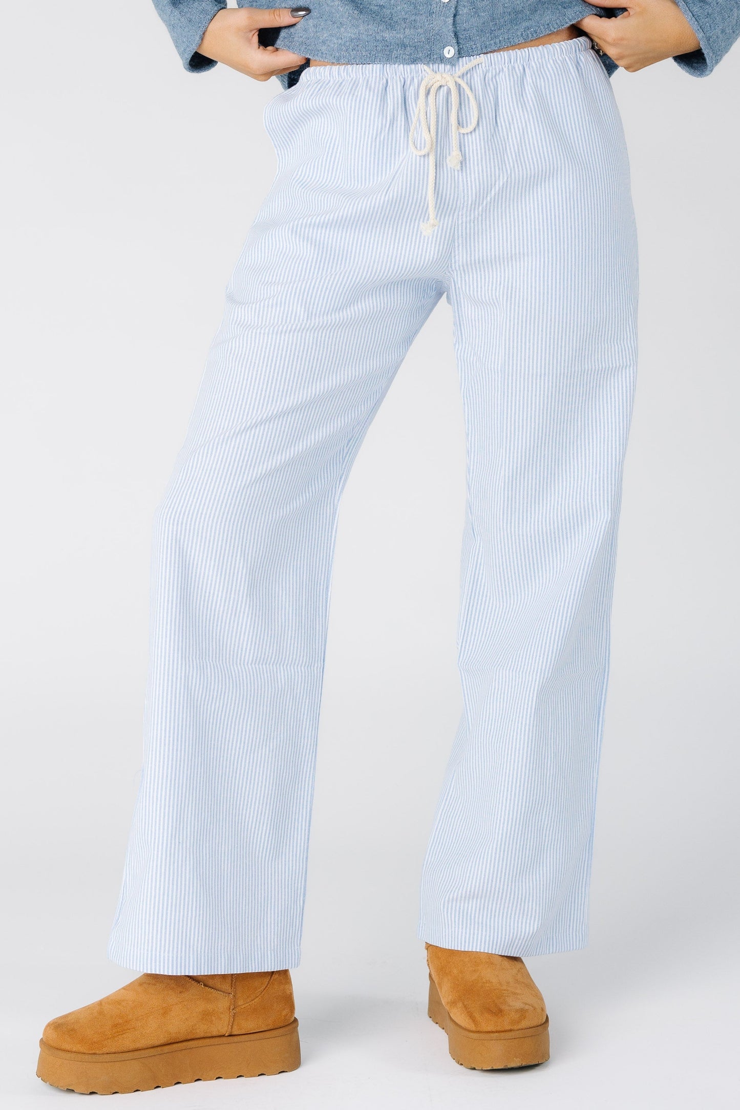 Woman wearing a pair of bule and white stripe pants with drawstring waist