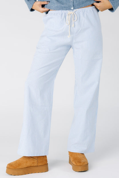 Woman wearing a pair of bule and white stripe pants with drawstring waist