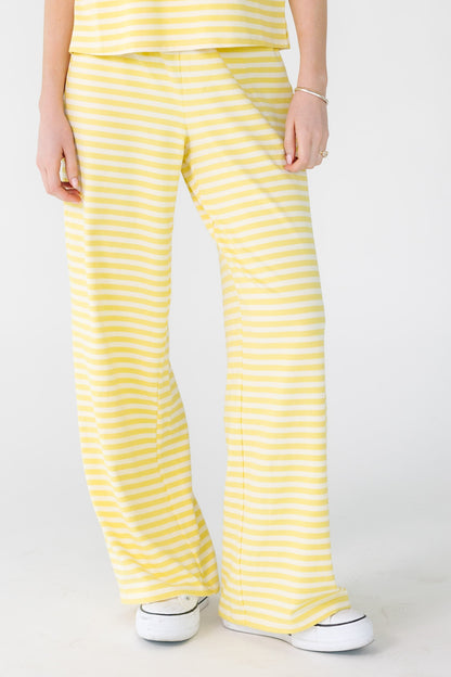 Woman wearing loose fitting yellow and white stripe lounge pants.