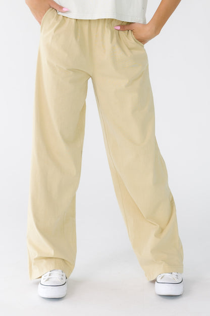 Young woman wearing a pair of light beige wide leg pants with side pockets.