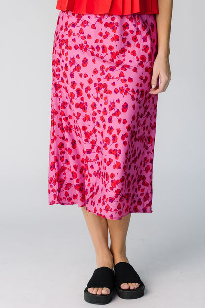 Woman wearing a modest pink A-line midi skirt with a red floral print. 
