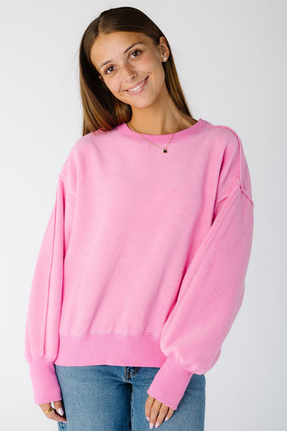 Woman wearing a loose fitting pink sweatshirt with exposed seams